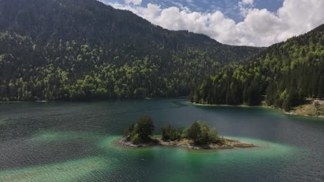 the crystal-clear eibsee lake in grainau, germany surrounded by lush forests and rugged mountains, aerial view