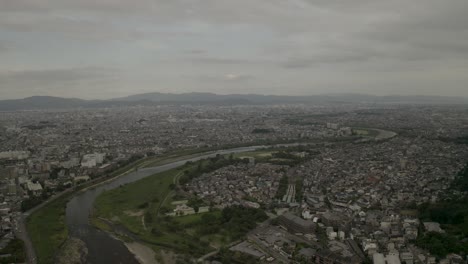 Aerial-Drone-Shot-of-Kyoto-at-Sunset-near-a-river,-Japan,-Asia