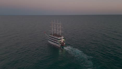 luftaufnahme kreisender mehrstufiger touristischer segelschiff, der über den friedlichen sonnenuntergang im mittelmeer kreuzt