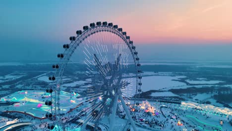 aerial drone shot of snowflake ferris wheel at sunset with beautiful colors at harbin ice festival in heilongjiang, china