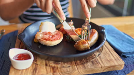 a dinner cuts into a meal of sausage, tomatoes, and bread all being served up in an iron skillet with catsup on the side