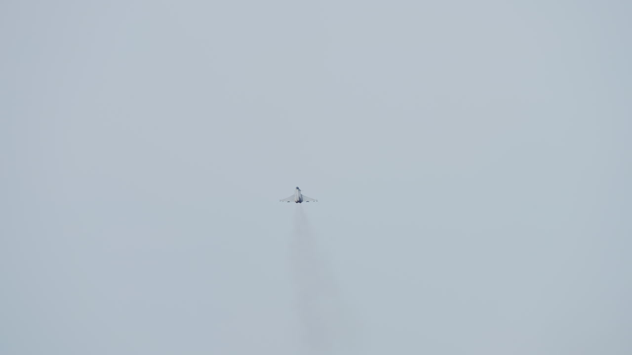 Jet da combattimento che si allontana in cielo sereno con scia di condensazione