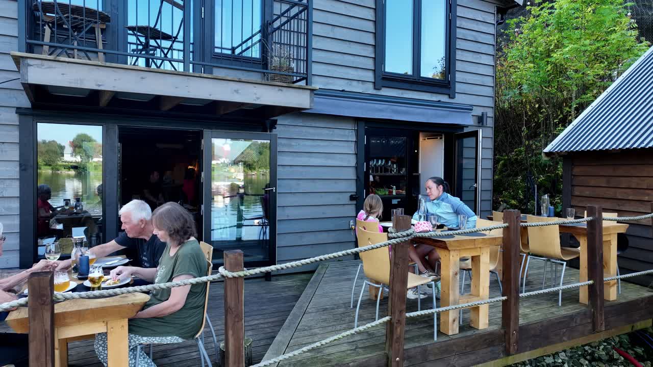 Mother and daughter dining moment at Mjoesvagen restaurant, then reveals more guests in cozy fjordside setting