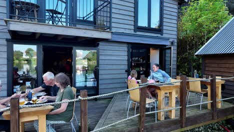 mother and daughter dining moment at mjoesvagen restaurant, then reveals more guests in cozy fjordside setting
