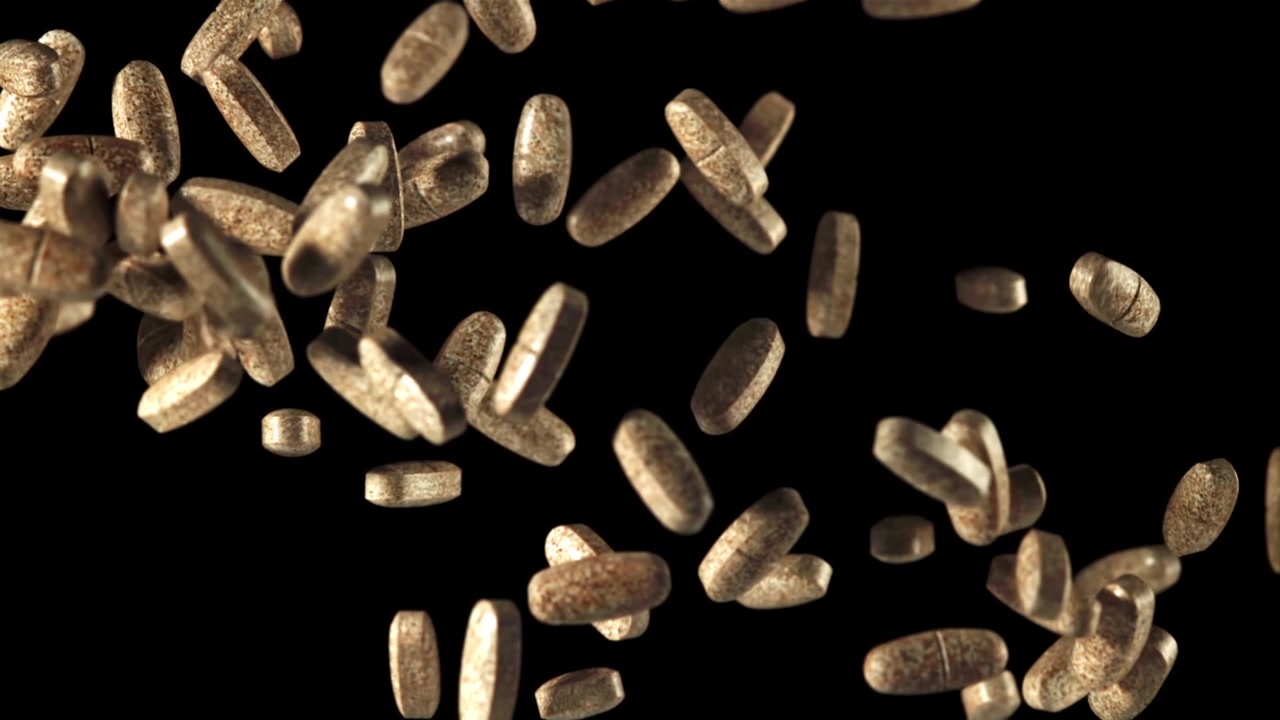 Pillole farmaceutiche marroni che cadono al rallentatore su sfondo nero