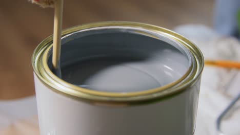 Wooden-Stick-Stirring-Grey-Color-Paint-in-Can.repair,-painting-and-home-improvement-concept--wooden-stick-stirring-thick-grey-color-paint-in-can