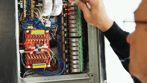 los electricistas ponen las manos a probar la corriente eléctrica en el panel de control. el ingeniero electricista trabaja midiendo el voltaje y la corriente de la línea eléctrica en el control del gabinete eléctrico.