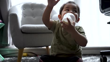 Niño-De-18-Meses-Bebiendo-Leche-Mientras-Está-Sentado-En-El-Suelo-En-Casa