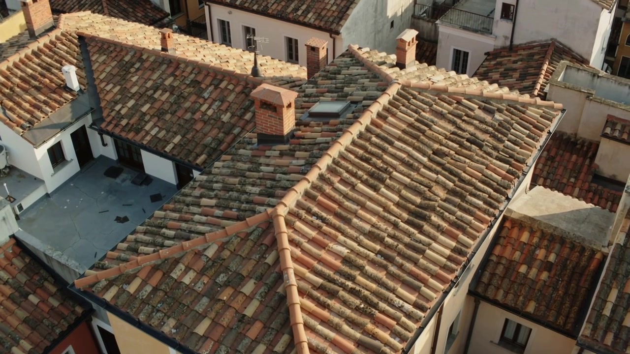 Telecamera drone che si avvicina rivelando tegole in terracotta con due camini in mattoni per mostrare la texture.