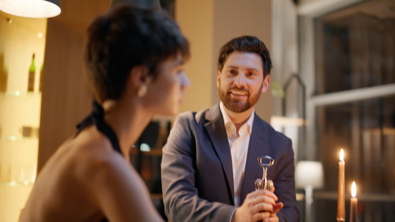 Enamoured pair celebrating anniversary hotel closeup. Gentleman opening bottle