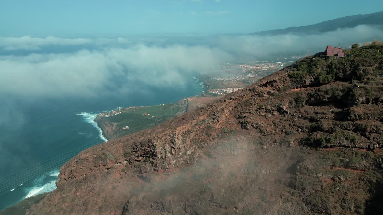 hermosa toma aérea de reenvío de montañas nubladas con el océano de fondo