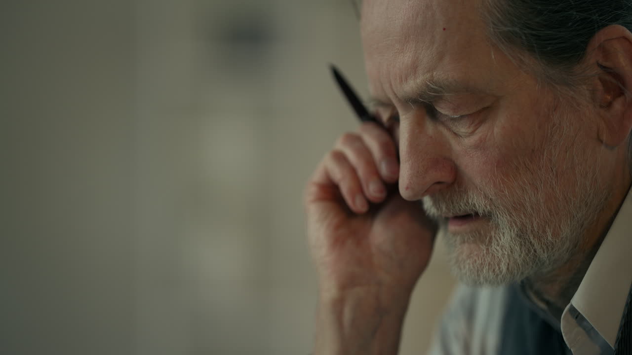 Close-up of Thoughtful Senior Man Pondering with a Pen