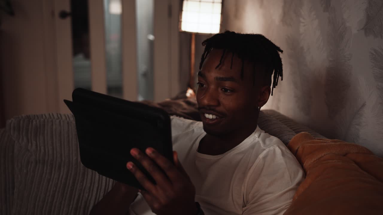 Young black male plays a game intently on his a tablet device