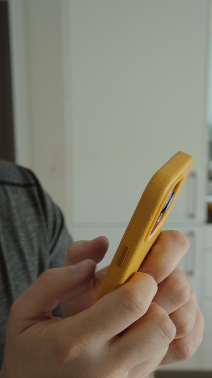 Primo piano di mani che digitano su uno smartphone con una custodia gialla, che rappresenta la messaggistica, la comunicazione e l'interazione digitale