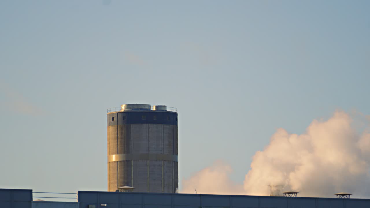 Industrial Pollution with Slow Motion Smoke Rising from Factory Building as CO2 is Released into Atmosphere. Climate Change Fuelled by Human Activity