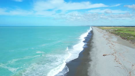 High-aerial-following-breaking-waves-onto-stony-beach-at-Canterbury-Bight---beautiful-turquoise-colored-South-Pacific-Ocean