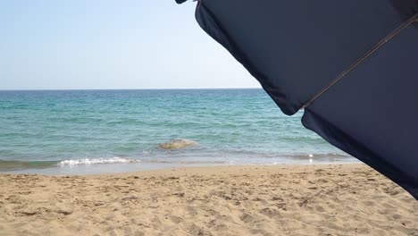 dos segmentos de un paraguas soplando a medida que la marea entra en la playa de arena