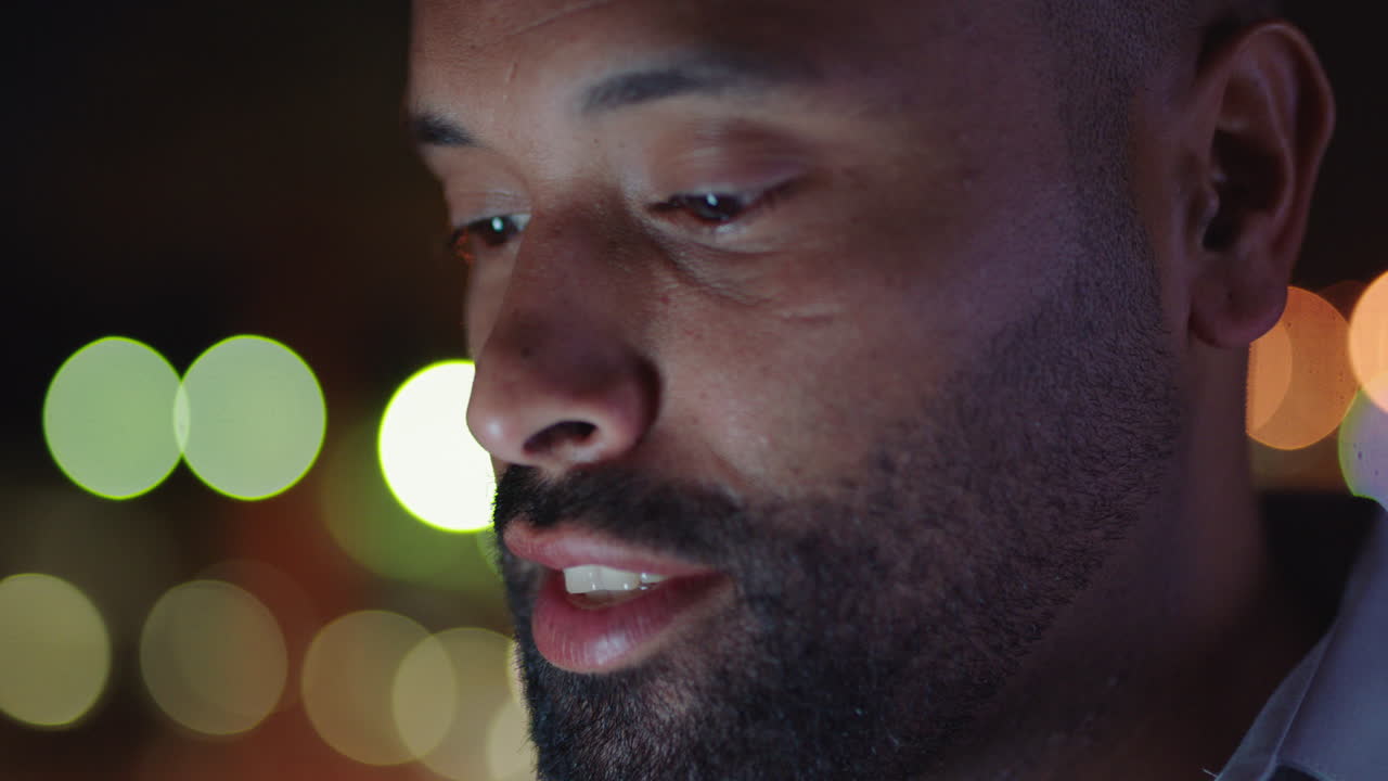 밤에 호텔 방에서 스마트폰을 사용하는 매력적인 남자가 온라인을 탐색하고 소셜 미디어 메시지를 확인하고 모바일 기술을 즐기고 있습니다.