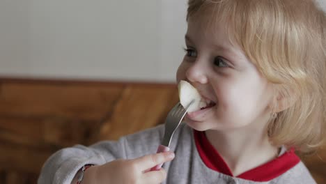 Little-girl-eats-pieces-of-fresh-pear-with-a-fork.-Child-eating-tasty-fruits