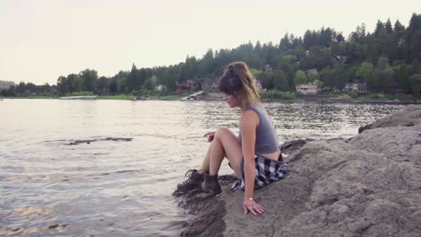 cute hipster girl sitting down by the edge of the water