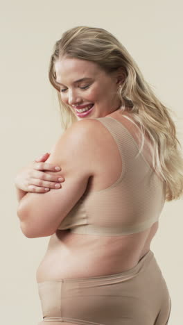 vertical video: smiling plus size woman in beige underwear embracing body positivity