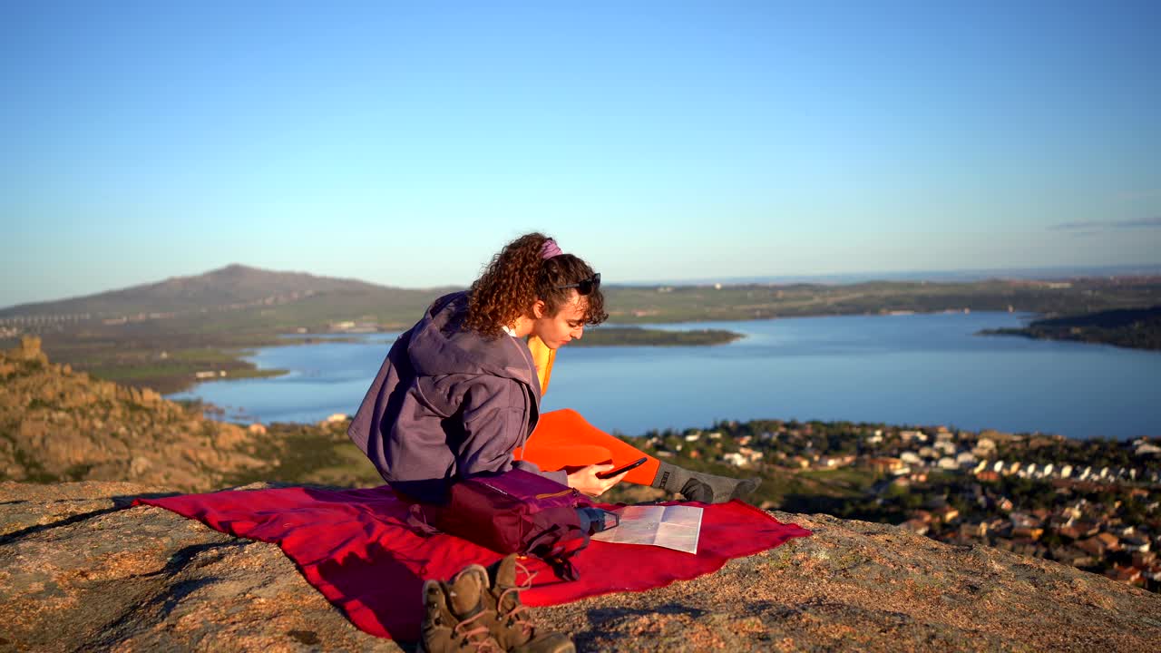 mujer feliz tomando una selfie y comiendo un sándwich cerca del lago de montaña