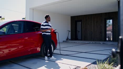 man charging electric car at home