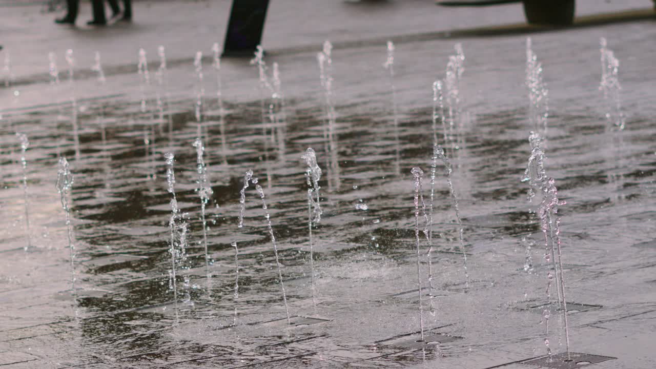 Slow Motion Water Fountain with Streams of Fluid Lines Ascending from Concrete Floor Outside. Granary Square Fountains in London