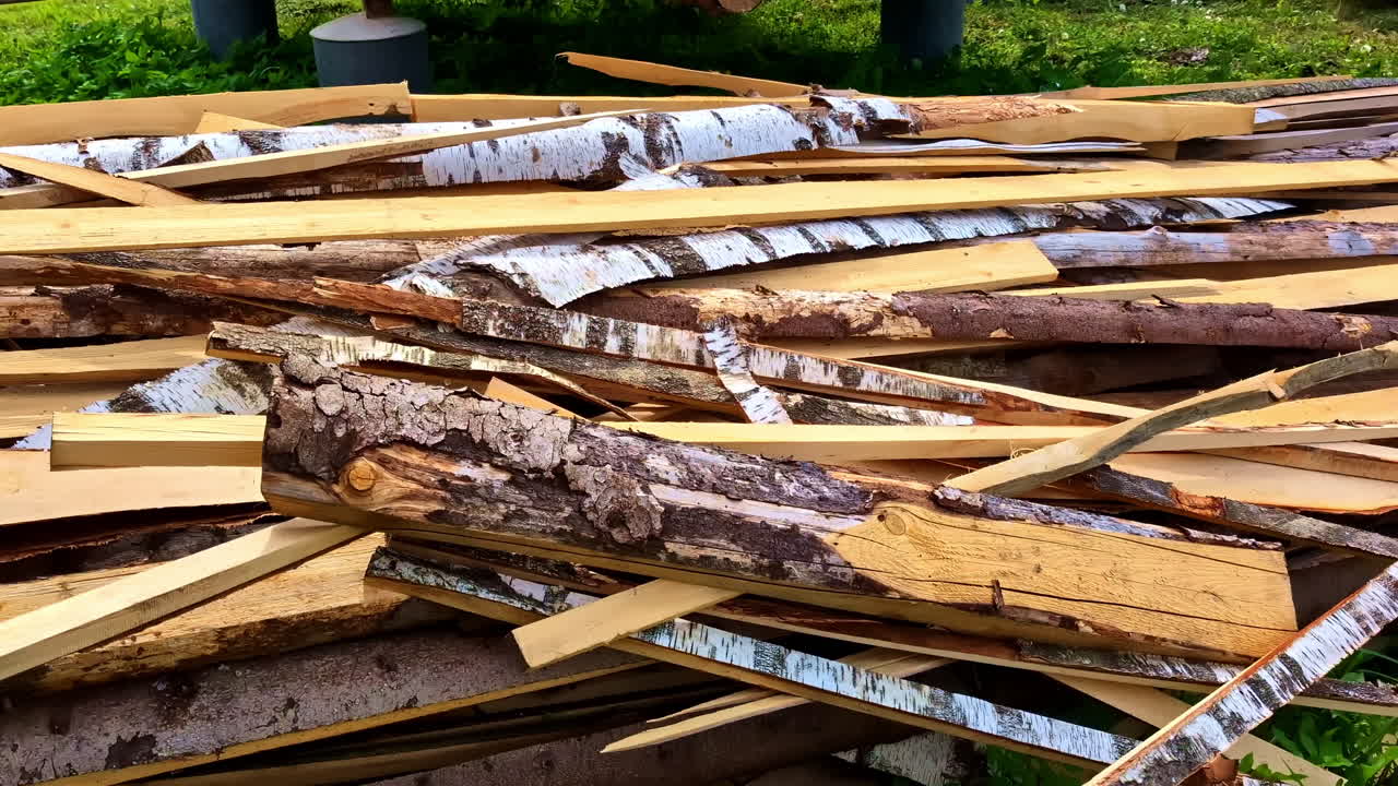 Mixed pile of bark-covered slab wood and peeled timber scraps stacked outdoors near sawmill