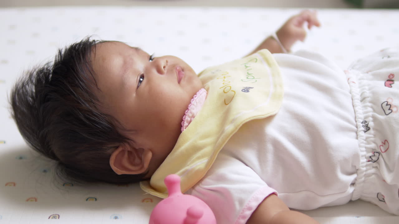 The baby is lying down, visibly upset and frustrated, capturing a natural moment of emotion and reaction in early development.