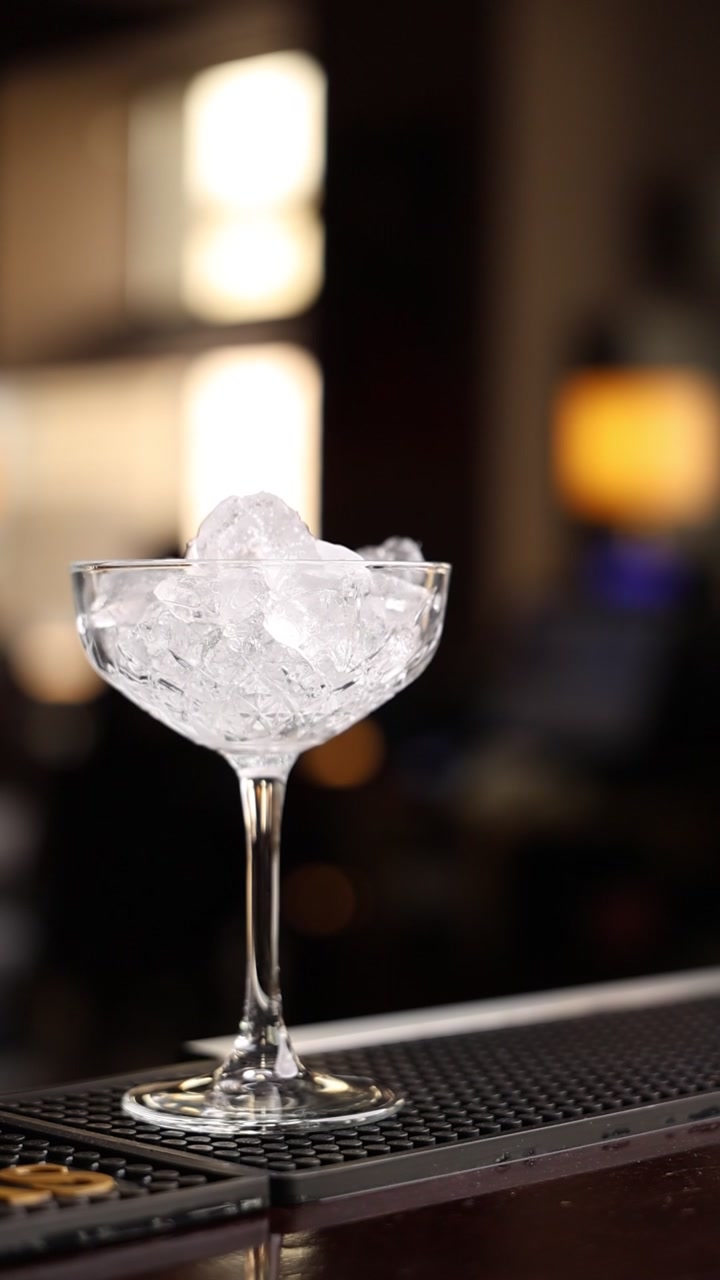Bicchiere da cocktail vuoto riempito con ghiaccio tritato su un bancone da bar