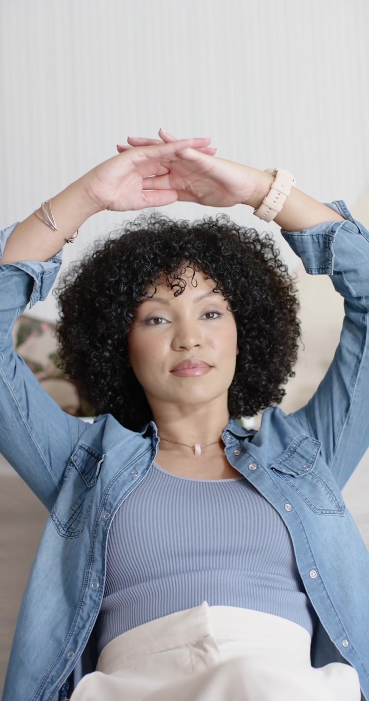 Vertical video: Sitting on sofa, woman in denim raising arms up, relaxing showing round panel