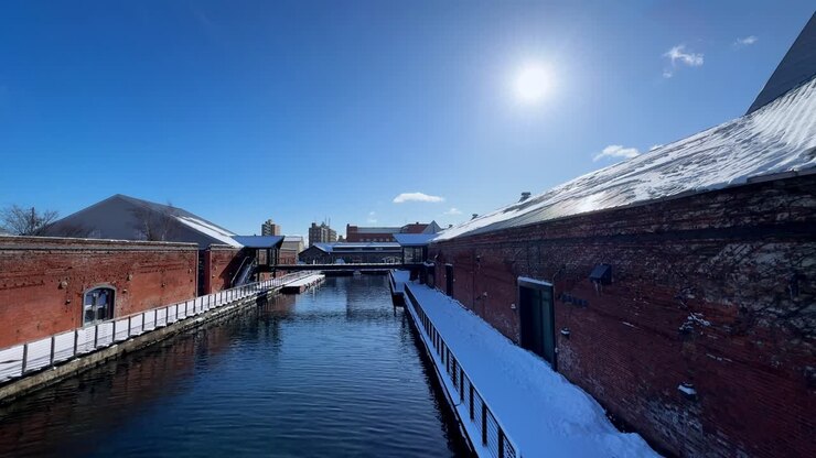 Canale innevato tra edifici in mattoni rossi sotto un cielo azzurro terso a Hakodate