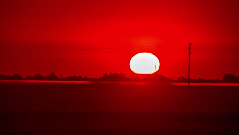 el tiempo del amanecer con rojos vívidos, campos brumosos y siluetas en el horizonte