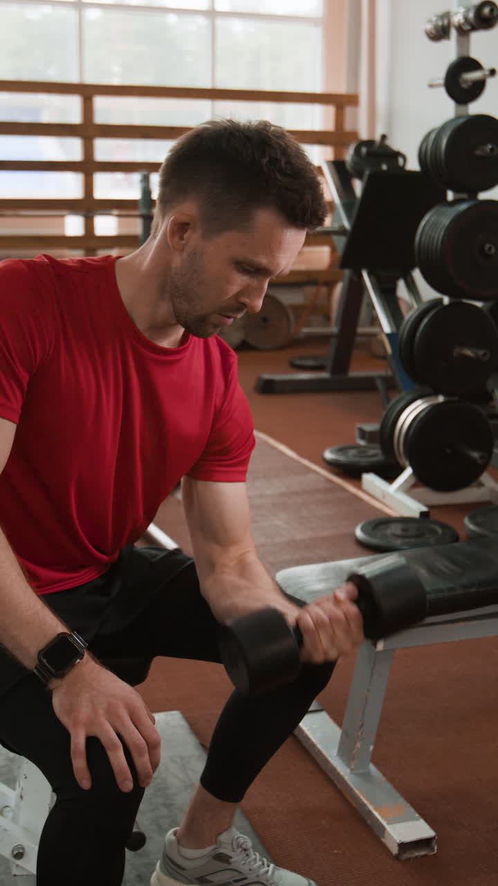 Muž provádějící bicepsové zdvihy s činkou v posilovně