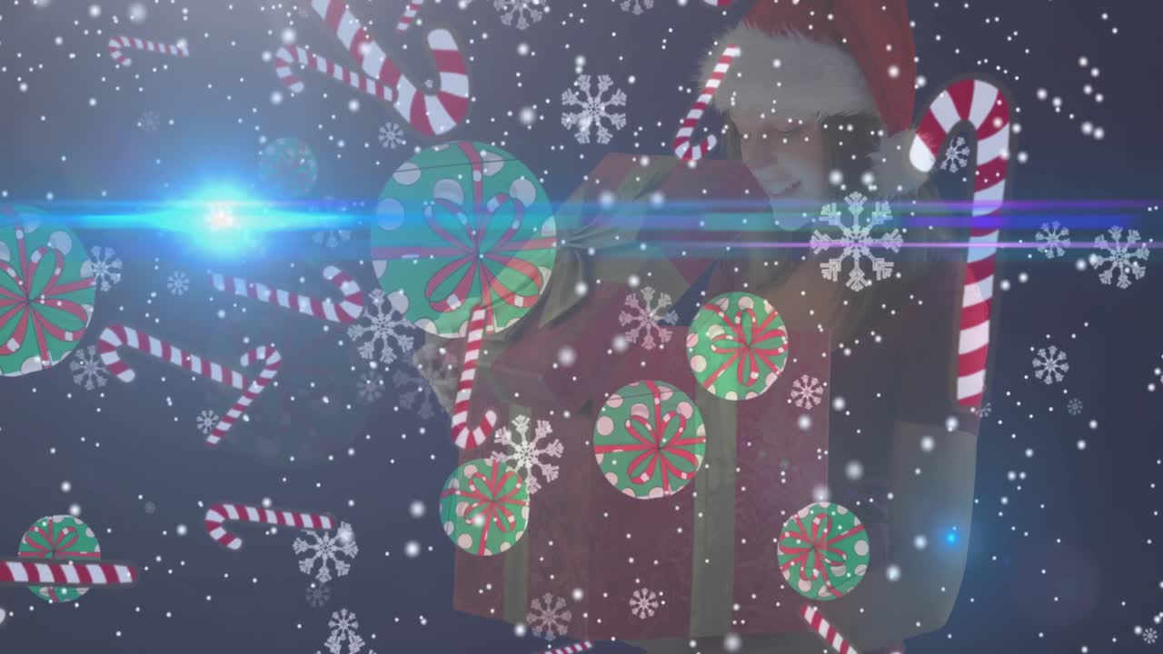 animación de nieve cayendo y decoraciones de navidad sobre feliz mujer caucásica manteniendo presente
