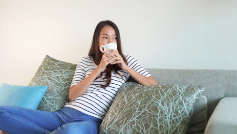 pretty asian girl smiling as she enjoys her morning cup of coffee