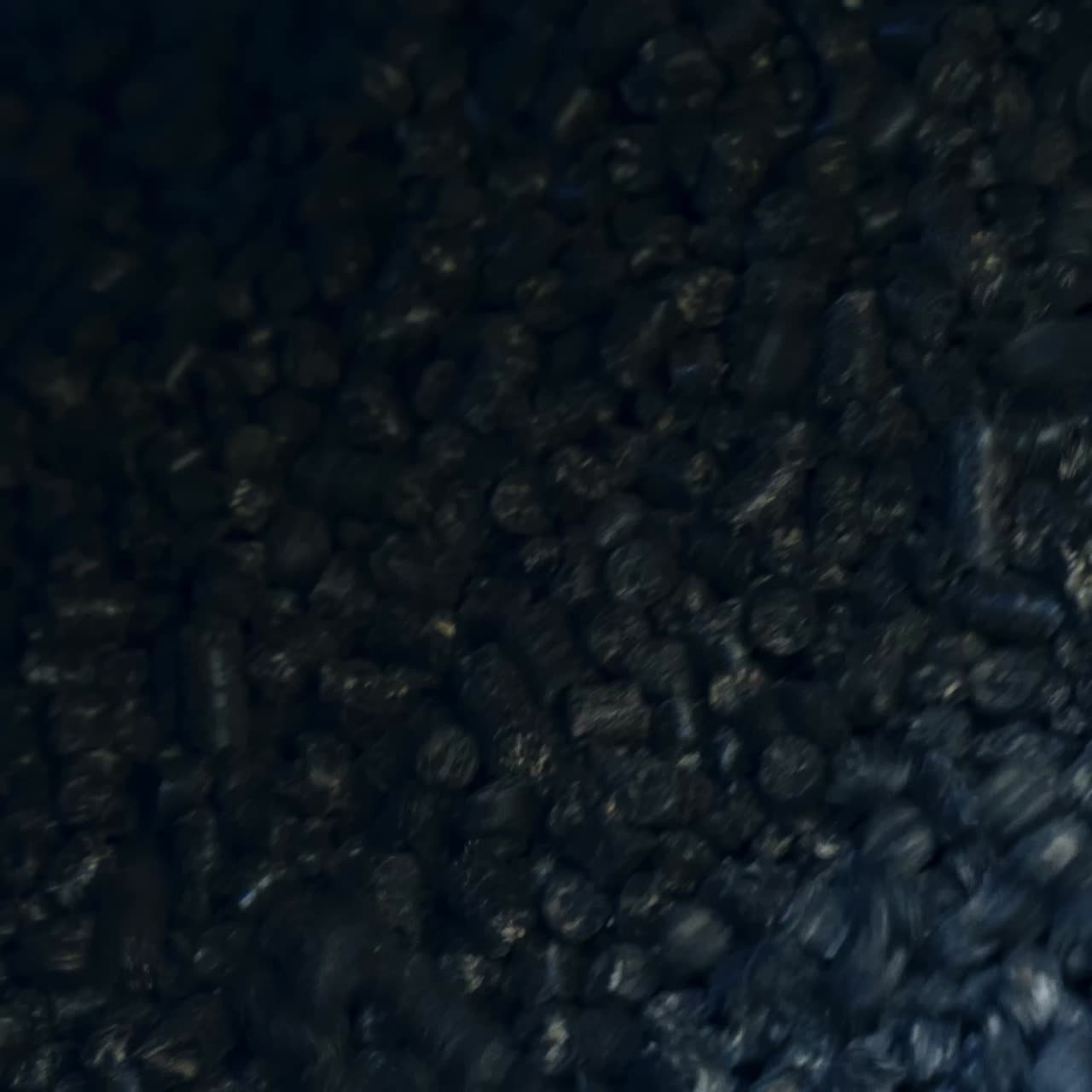 Shiny pieces of black charcoal falling down from the pipe. Pressed charcoal uploaded for heating the grain storage. Close up for charcoal background