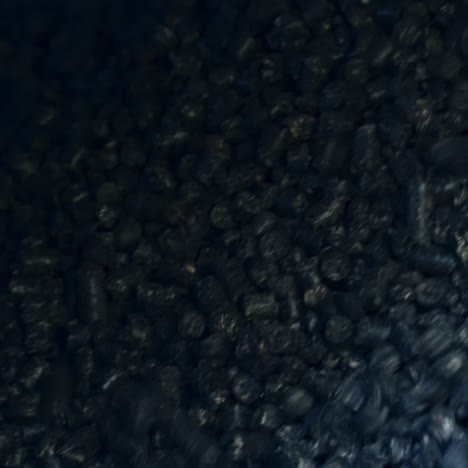 shiny pieces of black charcoal falling down from the pipe. pressed charcoal uploaded for heating the grain storage. close up for charcoal background