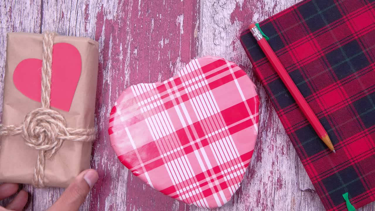regalo en forma de corazón y cuaderno en mesa de madera