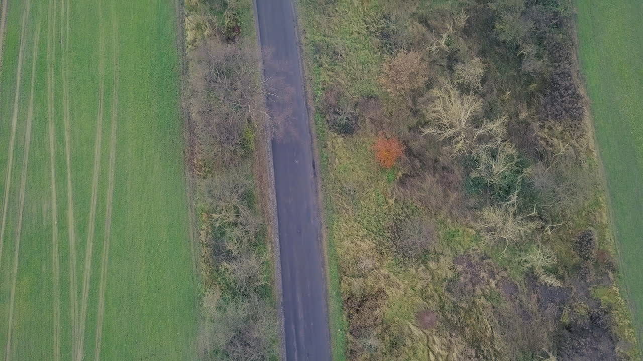 birdseye view from a drone flying above a road between grassland