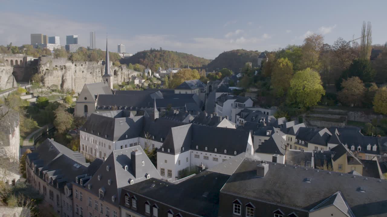 Wide shot capturing beautiful houses in Luxembourg, with the modern city and old castle ruins in the background on a sunny day