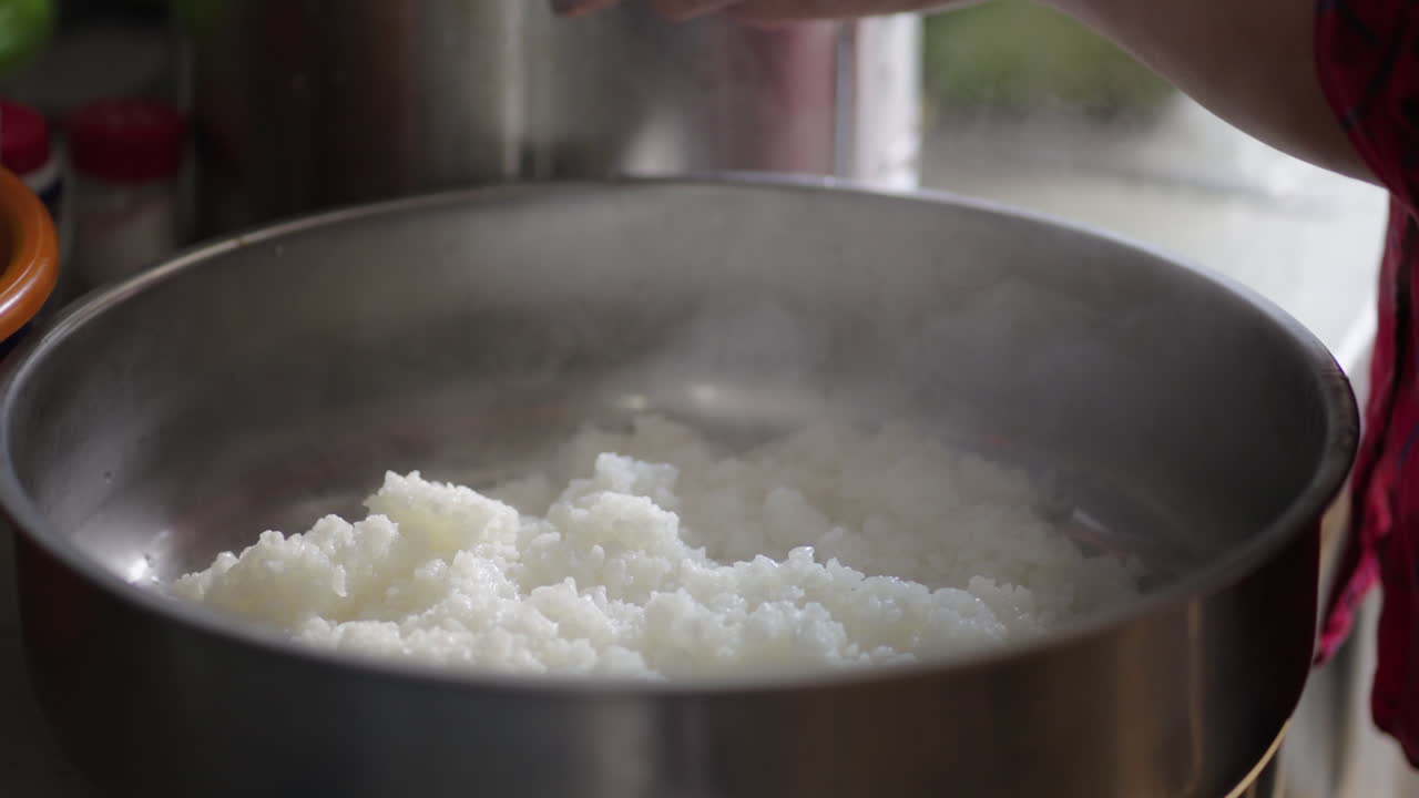 Close-up of hot rice cooking in a metal pot with steam rising from freshly cooked grains