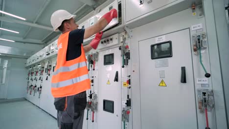 el ingeniero eléctrico que trabaja comprueba la tensión de corriente eléctrica y la sobrecarga en la parte delantera del gabinete del centro de carga o de la unidad de consumo para el mantenimiento en la sala principal del sistema de distribución de energía.