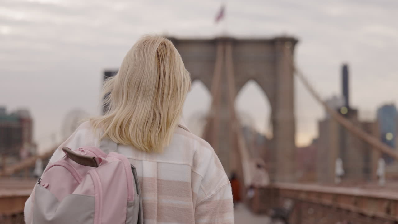 Giovane donna con zaino che cammina sul Ponte di Brooklyn