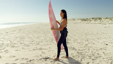 Surfista-Femenina-Poniendo-La-Tabla-De-Surf-En-La-Arena-4k-4k