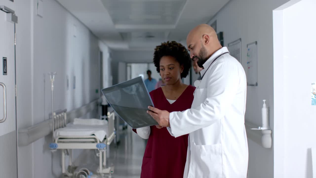 Diverse doctors discussing work and looking at x-ray scans in corridor, slow motion