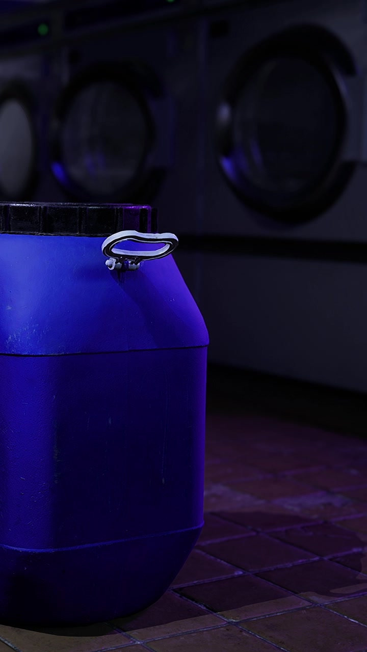 Blue container in a laundromat beside washing machines at night
