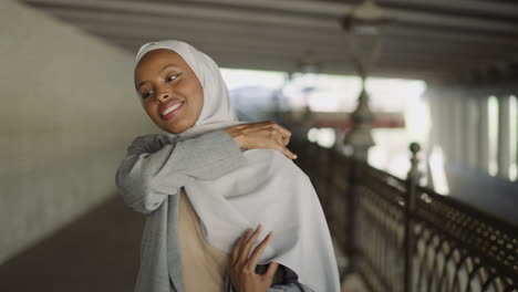 Smiling-black-woman-wraps-shoulder-with-hijab-on-waterfront