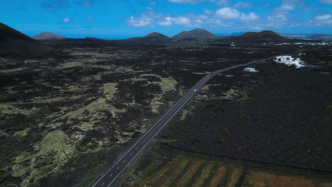 カナリア諸島のランサローテ島にあるラ・ヘリアの火山性溶岩原を貫く真っ直ぐな道。火山性の山々と青い空が広がる。